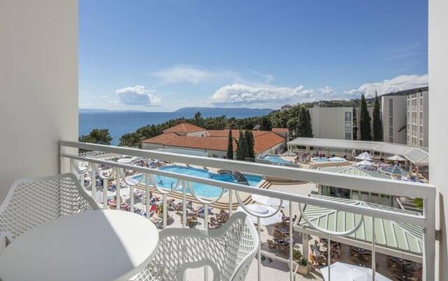 Balkon met uitzicht op het zwembad en de zee van Hotel Bluesun Alga in Dalmatië