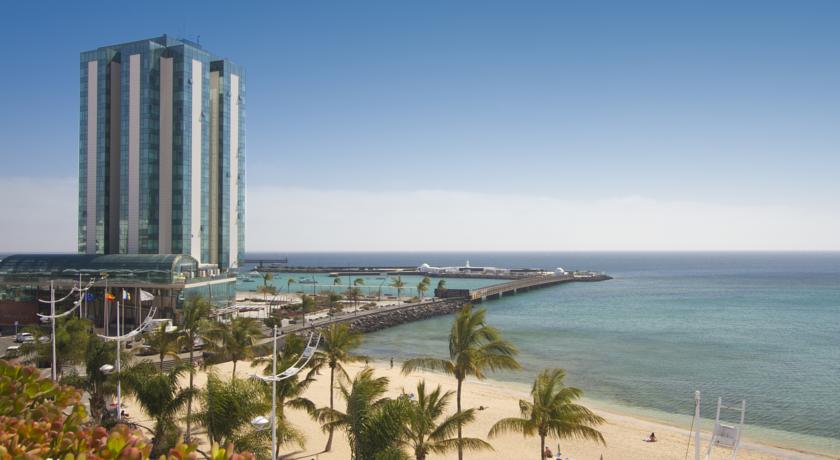 Uitzicht op het strand en een hoog gebouw vanaf hotel Lancelot op Lanzarote